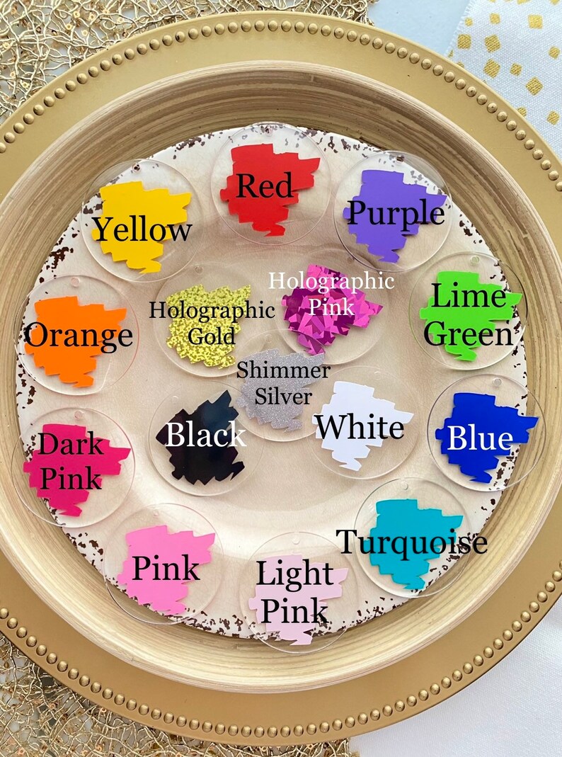 Peut inclure: Un ensemble de 14 pastilles de peinture acrylique rondes de diff&eacute;rentes couleurs et finitions, notamment rouge, violet, jaune, orange, vert lime, bleu, turquoise, rose, rose clair, rose fonc&eacute;, noir, blanc, or holographique et rose holographique. Les pastilles sont dispos&eacute;es en cercle sur une assiette dor&eacute;e.
