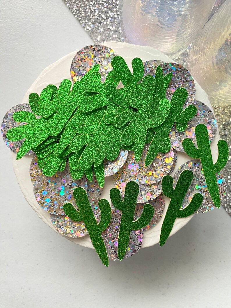 May include: Green glitter cactus and leaf shapes on a white background with iridescent glitter circles.