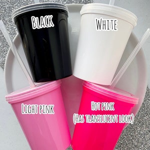 Peut inclure: Quatre gobelets en plastique avec couvercles et pailles. Les gobelets sont noirs, blancs, rose clair et rose fonc&eacute;. Le gobelet rose fonc&eacute; a un aspect translucide.