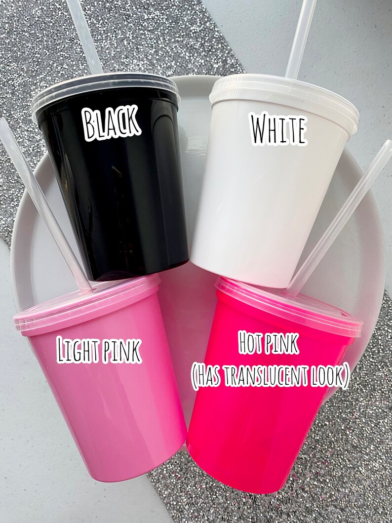 Peut inclure: Quatre gobelets en plastique avec couvercles et pailles. Les gobelets sont noirs, blancs, rose clair et rose fonc&eacute;. Le gobelet rose fonc&eacute; a un aspect translucide.