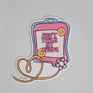 May include: A pink and blue sticker with a cartoon IV bag that says "Don't touch my pumps". The IV bag has a smiley face on it and a yellow tube with a flower on the end.