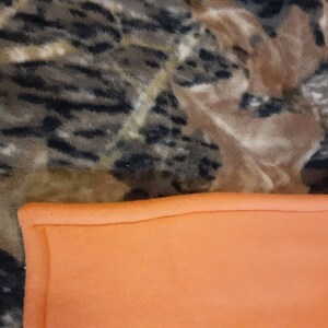 May include: A camouflage fleece blanket with a bright orange fleece lining. The blanket is soft and warm, ideal for keeping you cosy on cold days.