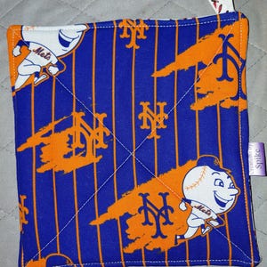 May include: A square fabric pot holder featuring a blue background with thin orange vertical pinstripes, the New York Mets logo, and a cartoon baseball character. It includes a white hanging loop with a red baseball stitch pattern and a side tag.