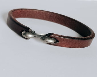 May include: A brown leather bracelet with a silver hook clasp.