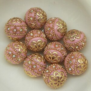 May include: Ten pink round beads with gold filigree designs and clear rhinestones.