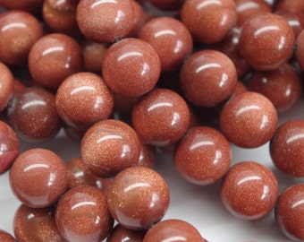 May include: A strand of round, brown and gold gemstone beads. The beads are smooth and have a shiny finish.