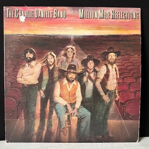 Op de afbeelding: Een vintage vinyl platenhoes met een band van vijf mannen in een podiumsetting. De albumhoes is getiteld "The Charlie Daniels Band Million Mile Reflections".