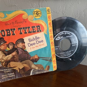 May include: A vintage 45 RPM record with a colorful cover featuring a cartoon image of Toby Tyler, a boy with a monkey, and a man. The record is titled "Biddle-Dee-Dee (I Go My Way)" and is a Walt Disney song. The record is a little golden record.