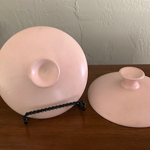 Puede incluir: Dos cuencos de cerámica rosa con un centro elevado en la parte inferior. Los cuencos están sobre una superficie de madera.