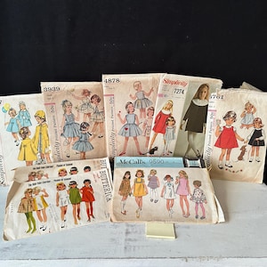 May include: A collection of vintage sewing patterns for children's clothing. The patterns feature illustrations of girls in various dresses and outfits. Brands include Simplicity, McCall's, and Butterick. The patterns are in various sizes and styles.