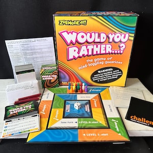 May include: A board game titled "Would You Rather...?" with a colorful box and game components. The box features the game's title in large, pink and white letters. The game includes cards, a game board, dice, and player pieces.