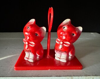 Dyrbara röda kattshakers i celluloidplast från 1950-talet med matchande bricka