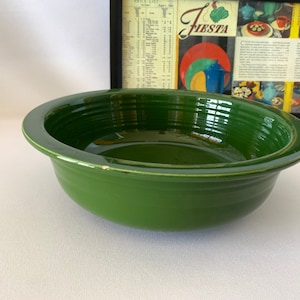 May include: A large, green ceramic serving bowl with a wide rim. The bowl has a glossy finish and is perfect for serving salads, pasta, or other dishes.