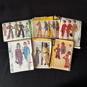 May include: A collection of vintage sewing patterns featuring various designs for women's clothing. The patterns are in various colors, including yellow, red, blue, and green. The patterns are from McCall's and Simplicity brands.