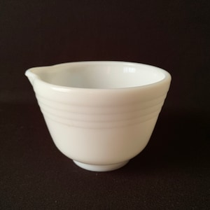 May include: White ceramic mixing bowl with a pouring spout. The bowl has a smooth, glossy finish and a slightly rounded shape.