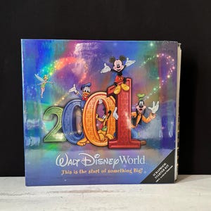 Puede incluir: Un kit de inicio de álbum de recortes de Walt Disney World con el año "2001" con Mickey Mouse, el Pato Donald, Goofy, Pluto y Campanilla. La portada tiene un diseño de arcoíris holográfico y el texto "This is the start of something Big!"