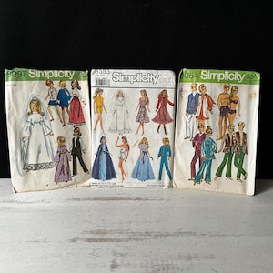 May include: Three vintage Simplicity sewing pattern envelopes. The patterns feature illustrations of women's and men's clothing, including dresses, suits, and swimwear. The envelopes are cream-colored with green and black text and illustrations.