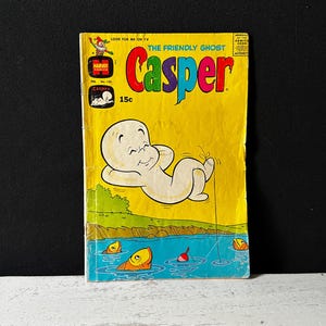 以下が含まれることがあります： カスペル、フレンドリーなゴーストをフィーチャーしたビンテージコミックの表紙。表紙は黄色で、タイトル「カスペル、フレンドリーなゴースト」は赤と黒の文字で書かれています。カスペルは白いシーツを着て、釣り竿を持って空中に浮いています。このコミックは15セントです。