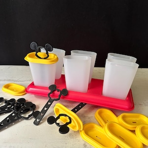 Puede incluir: Un juego de moldes para polos con temática de Mickey Mouse. El juego incluye moldes de plástico transparente, tapas amarillas, asas negras con forma de Mickey Mouse y una bandeja roja. Para hacer polos caseros.