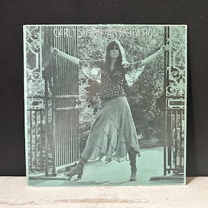 Puede incluir: Una taza de cerámica blanca con un asa negra y el texto "But First, Coffee" en negro, con una fuente de estilo manuscrito. La taza está sobre una superficie blanca.