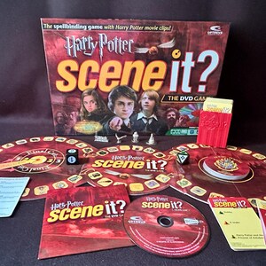 May include: A Harry Potter Scene It? DVD game set. The box features images of Harry, Ron, and Hermione. The game includes a game board, cards, dice, and game pieces. The game's theme is red and gold.