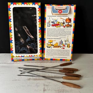 Può includere: Set per fonduta vintage con sei forchette in acciaio inossidabile con manici in legno. Il set include due scatole colorate con testo e illustrazioni. Le scatole hanno un bordo smerlato colorato.