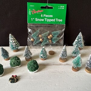 May include: A package of six 1-inch snow-tipped artificial Christmas trees. The trees are green with white tips and are packaged in a clear plastic bag with a green and white label that reads "6 Pieces 1" Snow Tipped Tree".
