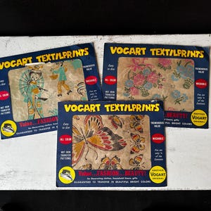 Puede incluir: Tres paquetes vintage de Vogart Text/LPrints. Cada paquete presenta un diseño diferente: una mujer con un paraguas, arreglos florales y mariposas. Los paquetes son azules con texto amarillo e incluyen las palabras "Value...Fashion...Beauty!" y "Washable."