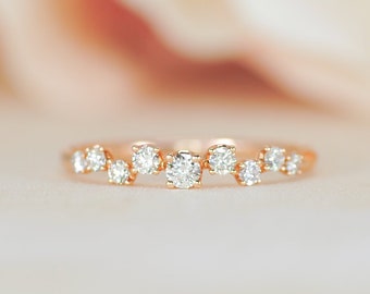 Könnte beinhalten: Ein zarter Goldring mit einer Reihe kleiner, runder Diamanten, die versetzt angeordnet sind.