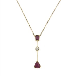 May include: A gold chain necklace with a pendant featuring three gemstones: a square red gemstone, a round clear gemstone, and a triangular red gemstone.