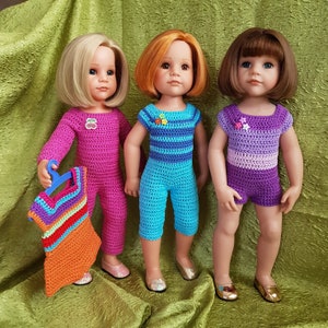 Könnte beinhalten: Drei Puppen in handgefertigten Häkel-Outfits. Die Puppe links trägt einen rosa Overall und hält ein buntes Neckholder-Top. Die mittlere Puppe trägt einen blauen Overall, und die rechte Puppe trägt ein lila Shorts-Set.