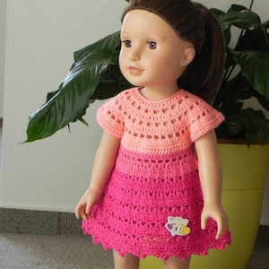 May include: A pink and peach crochet dress with short sleeves and a scalloped hem. The dress has a crocheted flower embellishment on the front.