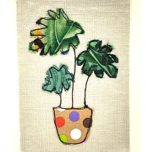 May include: A potted plant with three green leaves in a brown pot with white polka dots. The pot has red, orange, purple, and brown polka dots.