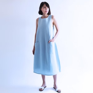 May include: A light blue sleeveless linen dress with two large pockets. The dress has a simple, straight cut and falls to the knees.