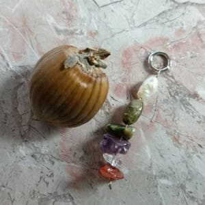 May include: A silver charm bracelet with a variety of colorful gemstones, including green, purple, red, and white. The bracelet is attached to a silver ring.
