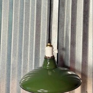 May include: A green metal pendant light with a wide, rounded shade. The shade has a glossy finish and a ribbed design. The light fixture hangs from a black cord and has a white ceramic socket.