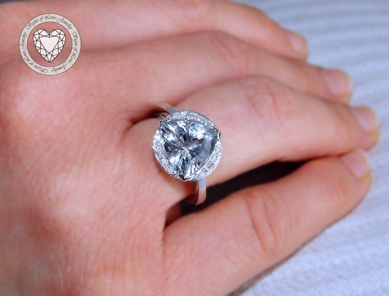 May include: A silver ring with a large, clear, heart-shaped gemstone surrounded by a halo of smaller, clear gemstones.