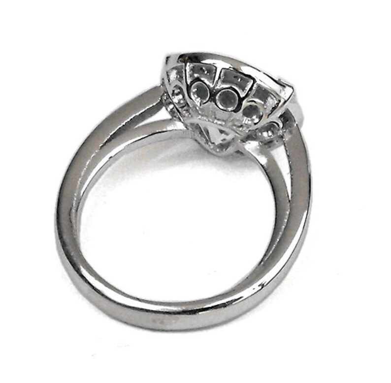 May include: A silver ring with a large, clear stone surrounded by smaller stones.