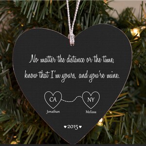 May include: A black heart-shaped Christmas ornament with white text that reads, "No matter the distance or the time, know that I'm yours, and you're mine." It includes the names Jonathan and Melissa, and the year 2015.
