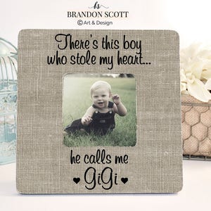 May include: A light brown picture frame with a burlap texture. The frame has a photo of a young boy in the center. The text "There's this boy who stole my heart... he calls me Gigi" is printed on the frame.