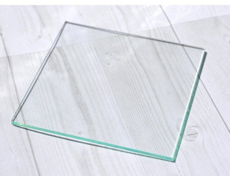 May include: A clear glass square with beveled edges.