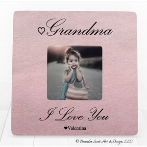 Op de afbeelding: Roze fotolijst met een witte passe-partout en een foto van een jong meisje. De lijst heeft de tekst "Grandma" bovenaan en "I Love You" met een hartje en de naam "Valentina" onderaan.
