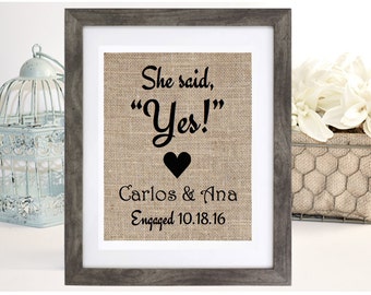 Puede incluir: Una impresión de arpillera enmarcada con el texto "She said, "Yes!" Carlos & Ana Engaged 10.18.16".