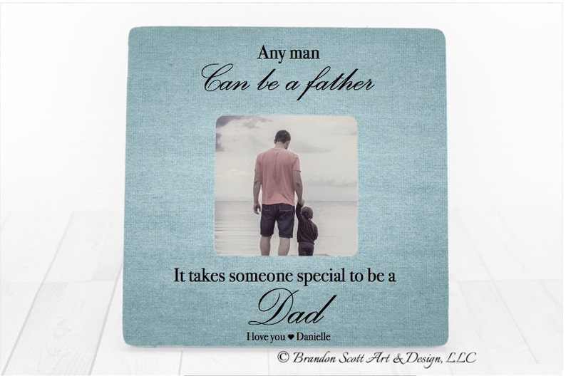 Puede incluir: Un marco de fotos azul claro con textura de lino blanco. El marco tiene una foto de un padre y un hijo caminando por la playa. El texto dice "Cualquier hombre puede ser un padre. Se necesita alguien especial para ser un pap&aacute;. Te amo Danielle. Brandon Scott Art & Design, LLC."