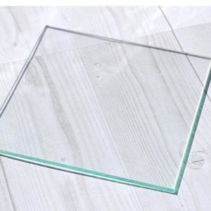 May include: A clear glass square with beveled edges.