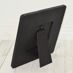 Puede incluir: Marco de fotos de madera negro con un caballete integrado en la parte posterior. El marco est&aacute; dise&ntilde;ado para contener una foto de 10x15 cm.