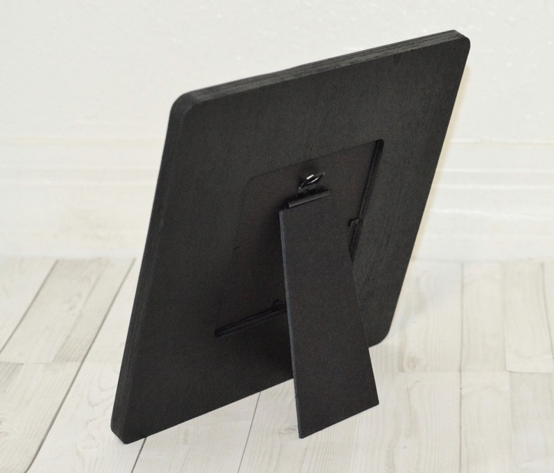 Puede incluir: Marco de fotos de madera negro con un caballete integrado en la parte posterior. El marco est&aacute; dise&ntilde;ado para contener una foto de 10x15 cm.