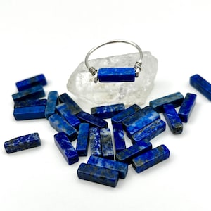 Puede incluir: Un anillo de plata con una piedra rectangular de lapisl&aacute;zuli. El anillo est&aacute; rodeado de muchas piedras peque&ntilde;as rectangulares de lapisl&aacute;zuli.