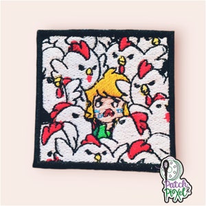 Könnte beinhalten: Gestickter Aufnäher mit einer Comicfigur mit blonden Haaren und einem grünen Hemd, umgeben von weißen Hühnern mit roten Kämmen. Die Figur hat einen verzweifelten Ausdruck und ist von Hühnern umgeben.