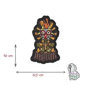 May include: Embroidered iron-on patch featuring a cartoon character with a mask, sitting on a tree stump. The character is wearing a green and brown outfit and has a yellow, red, and blue mask. The patch is 6.5 cm wide and 10 cm tall.